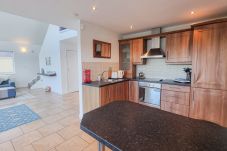 Riverrun Holiday Home No 15. Bright living room and open plan kitchen with counter.